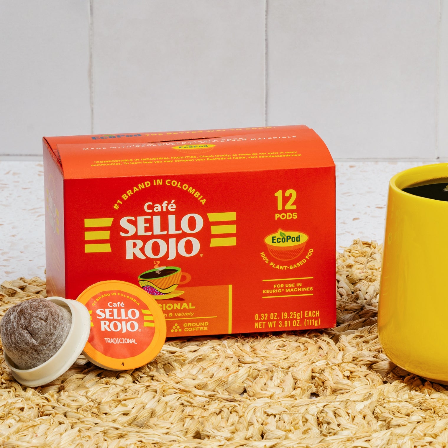 Café Sello Rojo coffee pod box with a yellow mug on a wooden surface